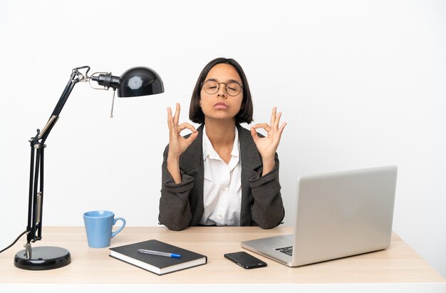 Jonge zakenvrouw van gemengd ras die op kantoor werkt in zen pose