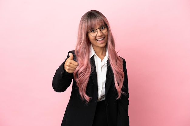 Jonge zakenvrouw van gemengd ras met roze haar geïsoleerd op roze achtergrond met duimen omhoog omdat er iets goeds is gebeurd