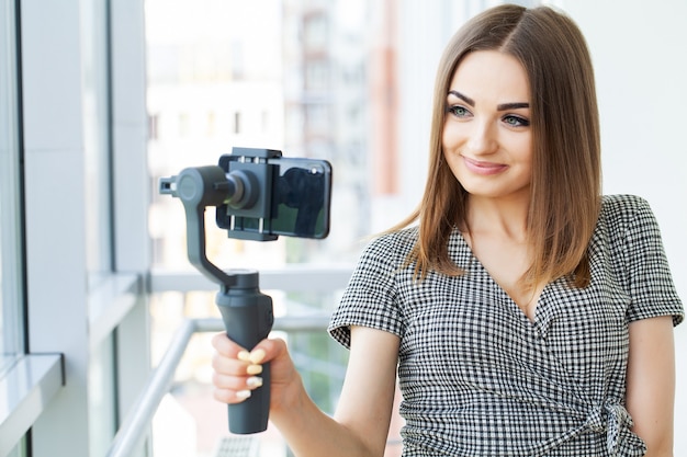 Jonge zakenvrouw video blog opnemen op smartphone in kantoor van het bedrijf.