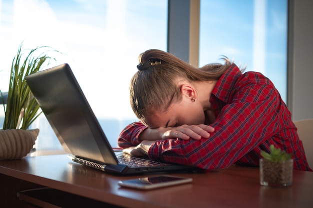 Jonge zakenvrouw viel in slaap op de werkplek. Je overwerkt en moe voelen na een lange werkdag op de computer