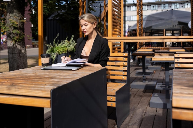 Jonge zakenvrouw zit in een café met een laptopdagboek