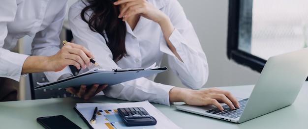 Jonge zakenvrouw zittend op kantoor aan tafel en smartphone gebruiken Op bureau is laptop en tabletcomputer op schermgrafieken en grafieken Vrouw die gegevens analyseert Student online leren