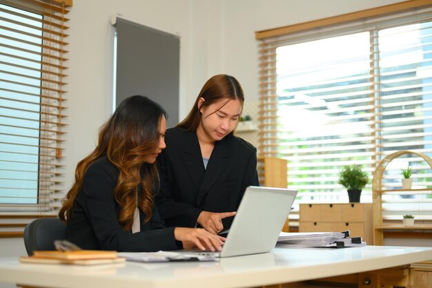 Jonge zakenvrouwen bespreken een nieuw bedrijfsproject en gebruiken een laptop op kantoor