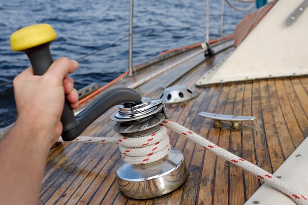 Jonge zeeman trekt touw op zeilboot