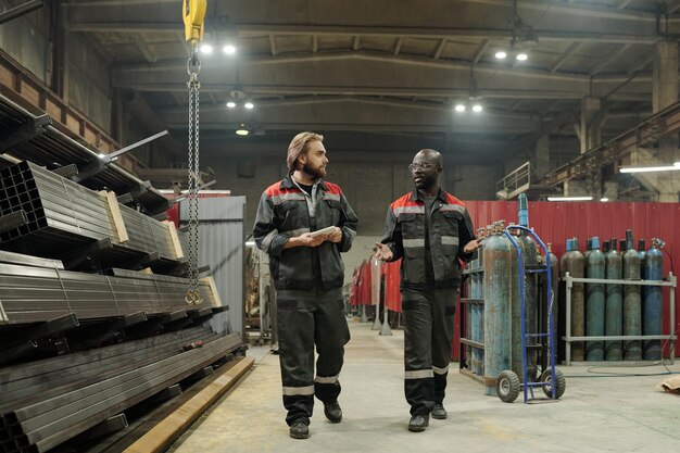 Foto jonge zelfverzekerde afro-amerikaanse ingenieur die onderweg met zijn collega praat