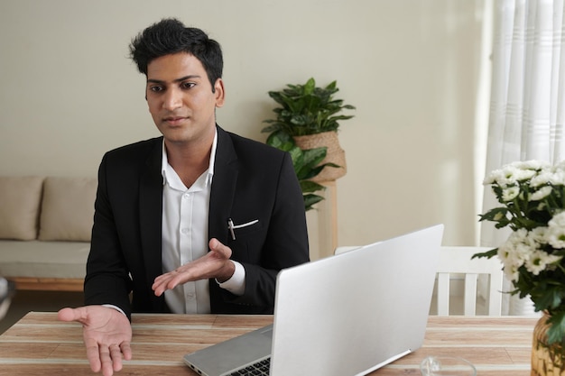 Jonge zelfverzekerde vastgoedverzekeringsagent in gesprek met klant op zijn kantoor