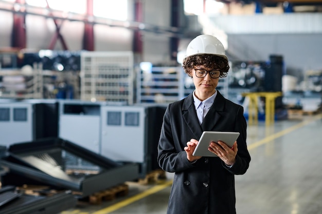 Jonge zelfverzekerde vrouwelijke ingenieur die door online technische gegevens kijkt