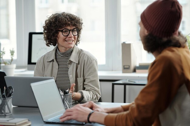 Jonge zelfverzekerde zakenvrouw die mannelijke collega bekijkt tijdens discussie