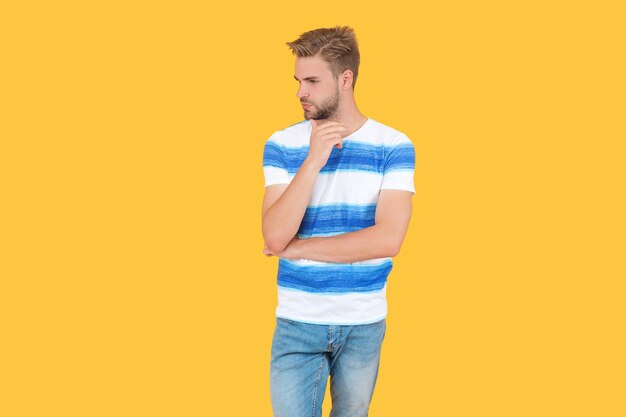 Jonge zomerman of kerel die een stijlvolle en trendy gestreepte zomert-shirt draagt die stijl toont die op gele studioachtergrond is geïsoleerd