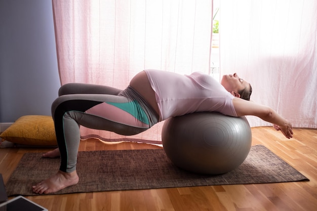 Jonge zwangere vrouw beoefent thuis yoga