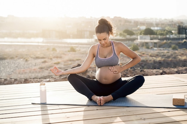 Jonge zwangere vrouw die buiten yoga doet - Focus op de rechterhand met buik right