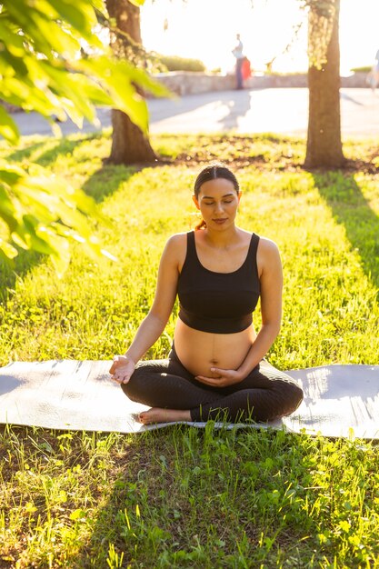 Jonge zwangere vrouw die in de natuur mediteert, beoefent yoga, zorg voor gezondheid en zwangerschap