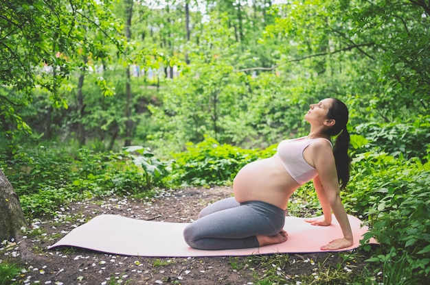 Jonge zwangere vrouw die yoga doet die in park uitoefent openlucht