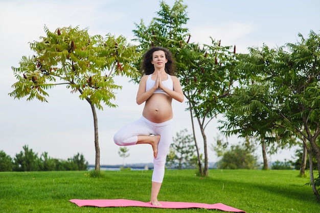 Jonge zwangere vrouw die yoga in openlucht doet