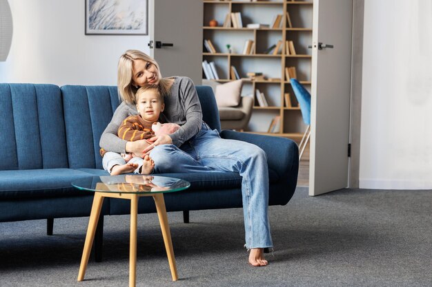 Jonge zwangere vrouw en haar zoon zitten thuis op de bank kleine jongen brengen samen tijd door en genieten van de communicatie met de kicks van de ongeboren baby