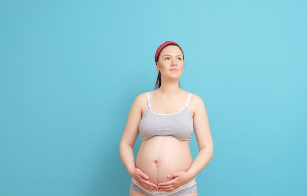 Jonge zwangere vrouw geïsoleerd op blauw