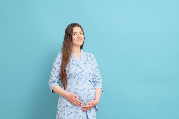 Jonge zwangere vrouw geïsoleerd op blauw