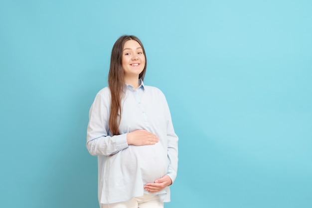 Jonge zwangere vrouw geïsoleerd op blauw