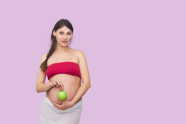 Jonge zwangere vrouw houdt een rijpe groene appel vast