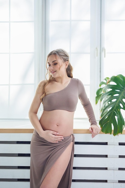 Jonge zwangere vrouw in beige top en rok Moederschap zwangerschap kopie ruimte Mode voor zwangerschap Gelukkige zwangerschapsperiode