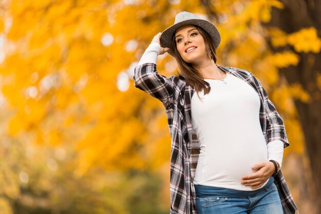 Jonge zwangere vrouw in het de herfstpark