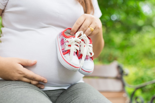 Jonge zwangere vrouw met baby schoenen aan haar buik