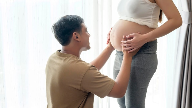 Jonge zwangere vrouw met echtgenoot die thuis een baby omhelst en verwacht