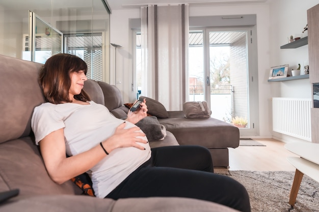 Jonge zwangere vrouw met zwangerschapsdiabetes zelftest om suiker thuis op de bank te controleren, positief testresultaat