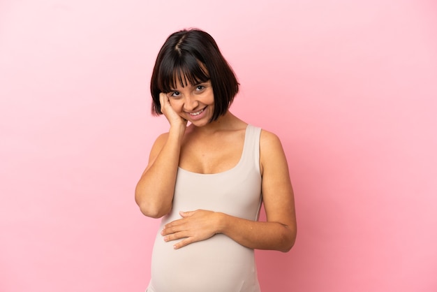 Jonge zwangere vrouw over geïsoleerde roze achtergrond lachen