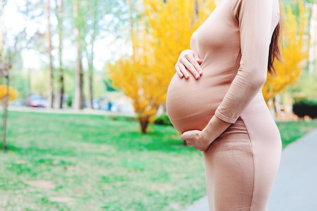 Jonge zwangere vrouw permanent buiten in stadspark en houden haar buik moederschap zwangerschap mensen en verwachting Concept