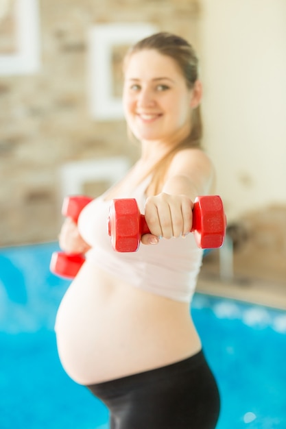 Jonge zwangere vrouw tillen halter op sportschool