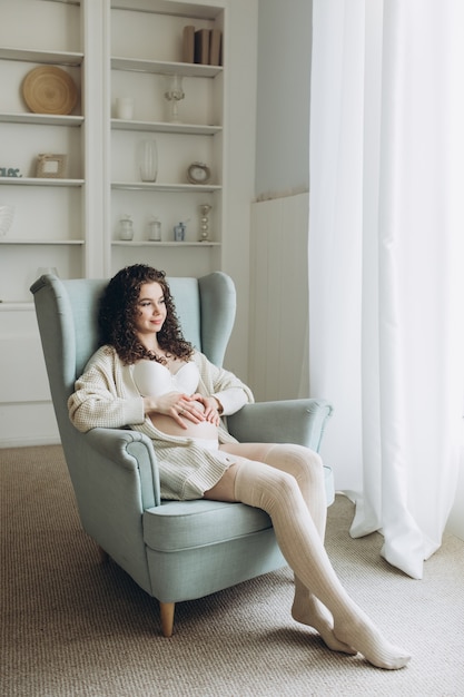 Jonge zwangere vrouw zittend op een fauteuil