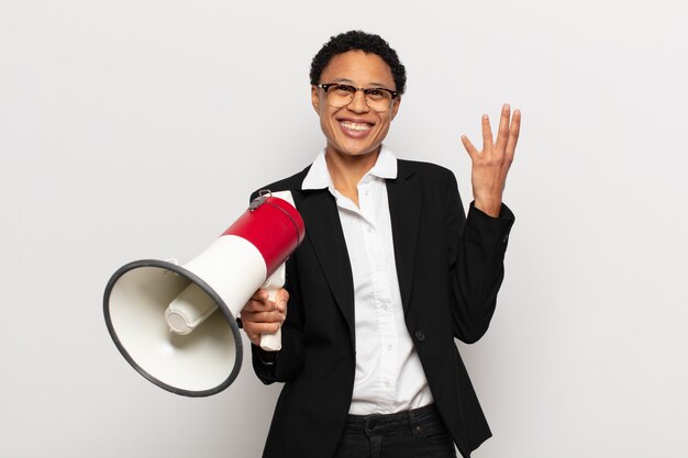 Jonge zwarte afro vrouw die zich blij, verrast en opgewekt voelt, glimlachend met een positieve instelling, een oplossing of idee realiserend