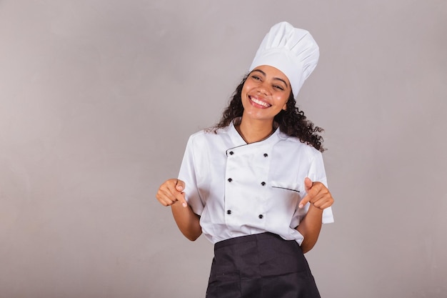 Jonge zwarte Braziliaanse vrouw kok masterchef wijst alleen hier naar het midden