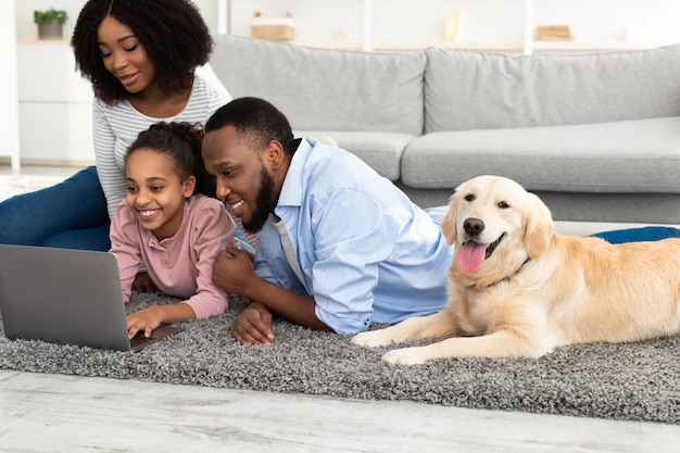 Jonge zwarte familie met hond die laptop met behulp van