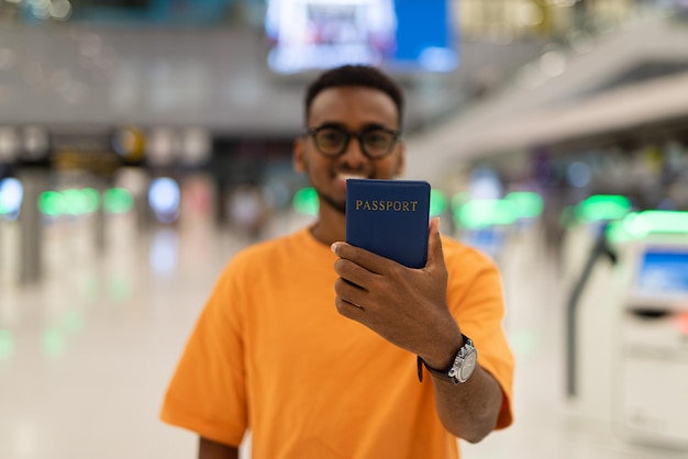 Jonge zwarte man klaar om te reizen op de luchthaventerminal en paspoort te tonen