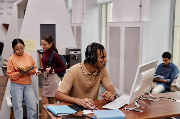 Jonge zwarte man met behulp van computer in universiteitsbibliotheek