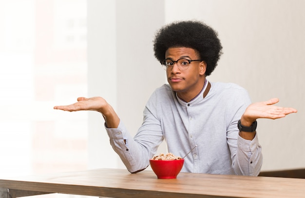 Jonge zwarte man met een ontbijt twijfelen en schouders ophalen