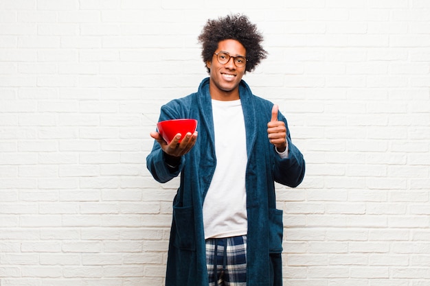 Jonge zwarte man met pyjama's met een ontbijtkom tegen br