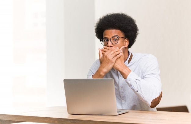 Jonge zwarte man met zijn laptop verrast en geschokt