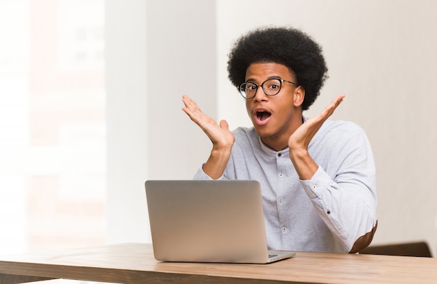 Jonge zwarte man met zijn laptop verrast en geschokt