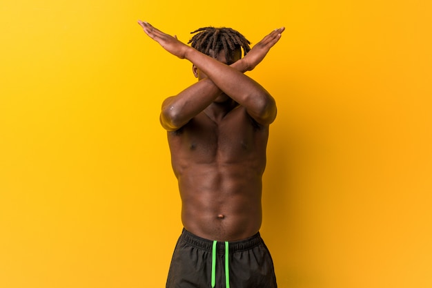 Jonge zwarte man shirtless dragen zwempak houden twee armen gekruist