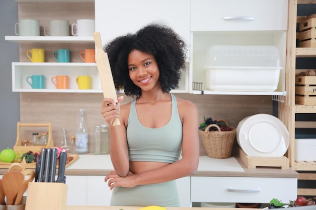 Jonge zwarte meid met afro-haarvrouw die fruit bereidt en eet voordat ze een smoothie maakt