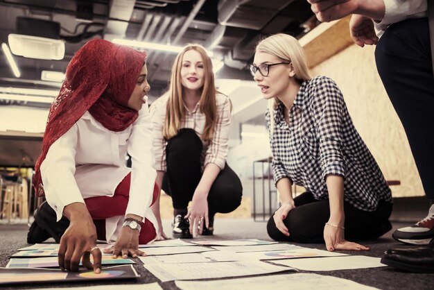 Foto jonge zwarte moslim zakenvrouw die een ontmoeting heeft met haar multi-etnische startup business team in een modern kantoorinterieur, die nieuwe ideeën op de vloer presenteert