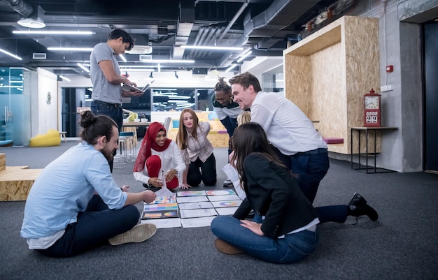 jonge zwarte moslim zakenvrouw die een ontmoeting heeft met haar multi-etnische startup business team in een modern kantoorinterieur, die nieuwe ideeën op de vloer presenteert