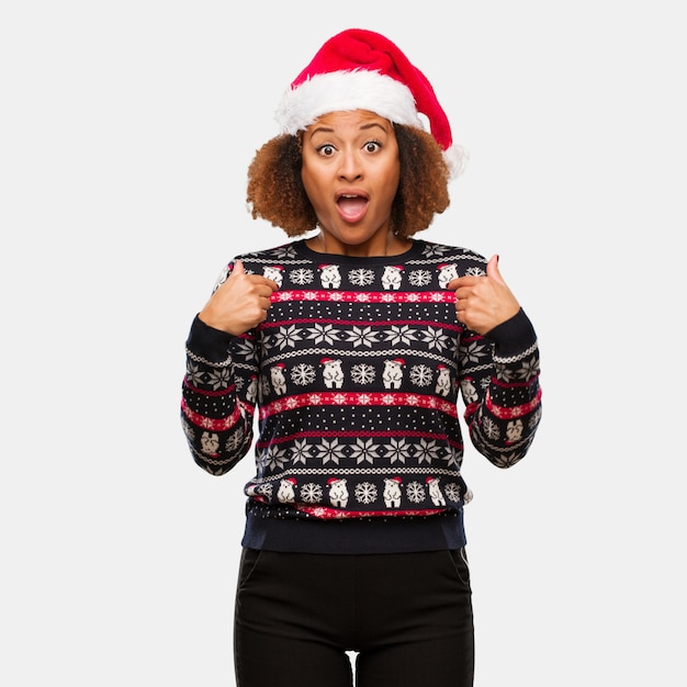 Jonge zwarte vrouw in een trendy kerst trui met print verrast, voelt zich succesvol