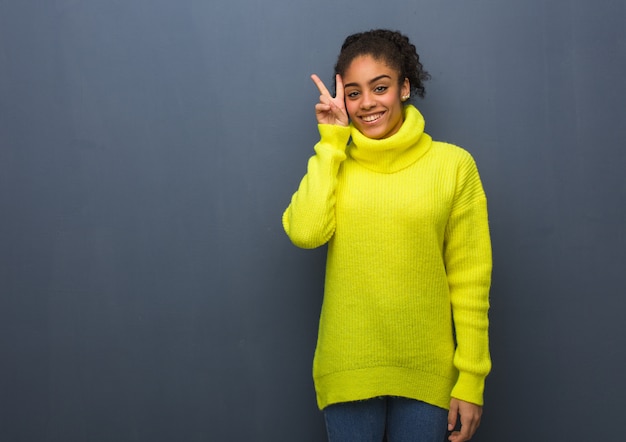 Jonge zwarte vrouw leuk en gelukkig doet een gebaar van overwinning