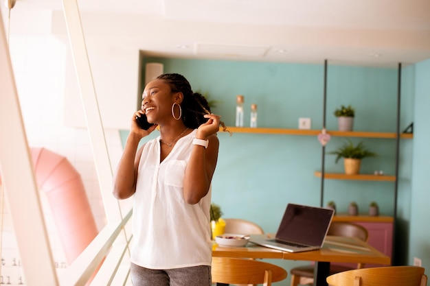 Jonge zwarte vrouw met behulp van mobiele telefoon in het café