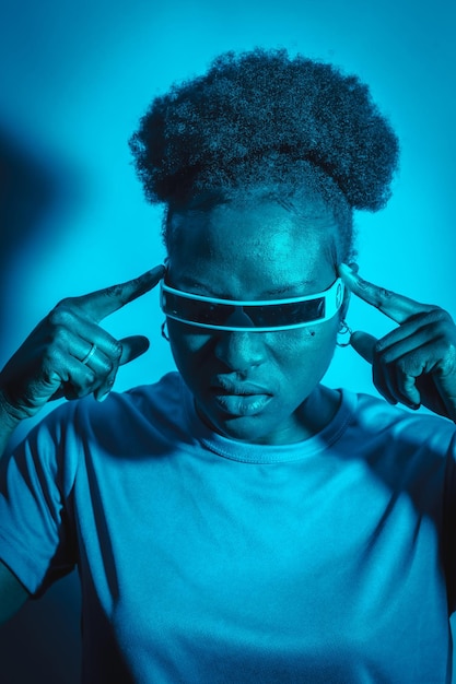 Jonge zwarte vrouw met een slimme bril op blauwe achtergrond Diverse jonge vrouw met een scifi-bril geïsoleerd op de achtergrond