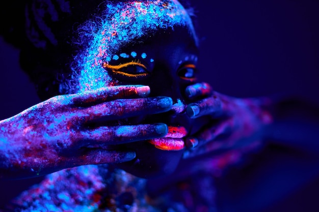 Foto jonge zwarte vrouw met fluorescerende prints op gezicht ongebruikelijke prints body art